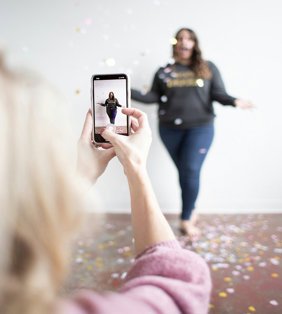 a woman holding a phone filming another woman dancing