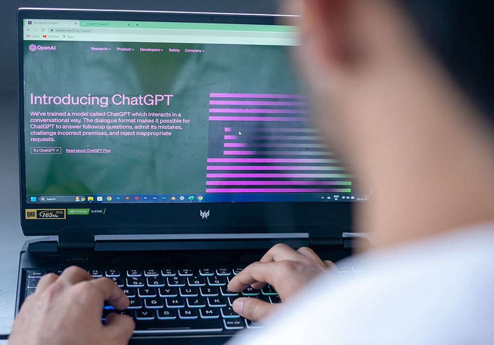 the neck and part of the head of a man facing a laptop showing information about ChatGPT